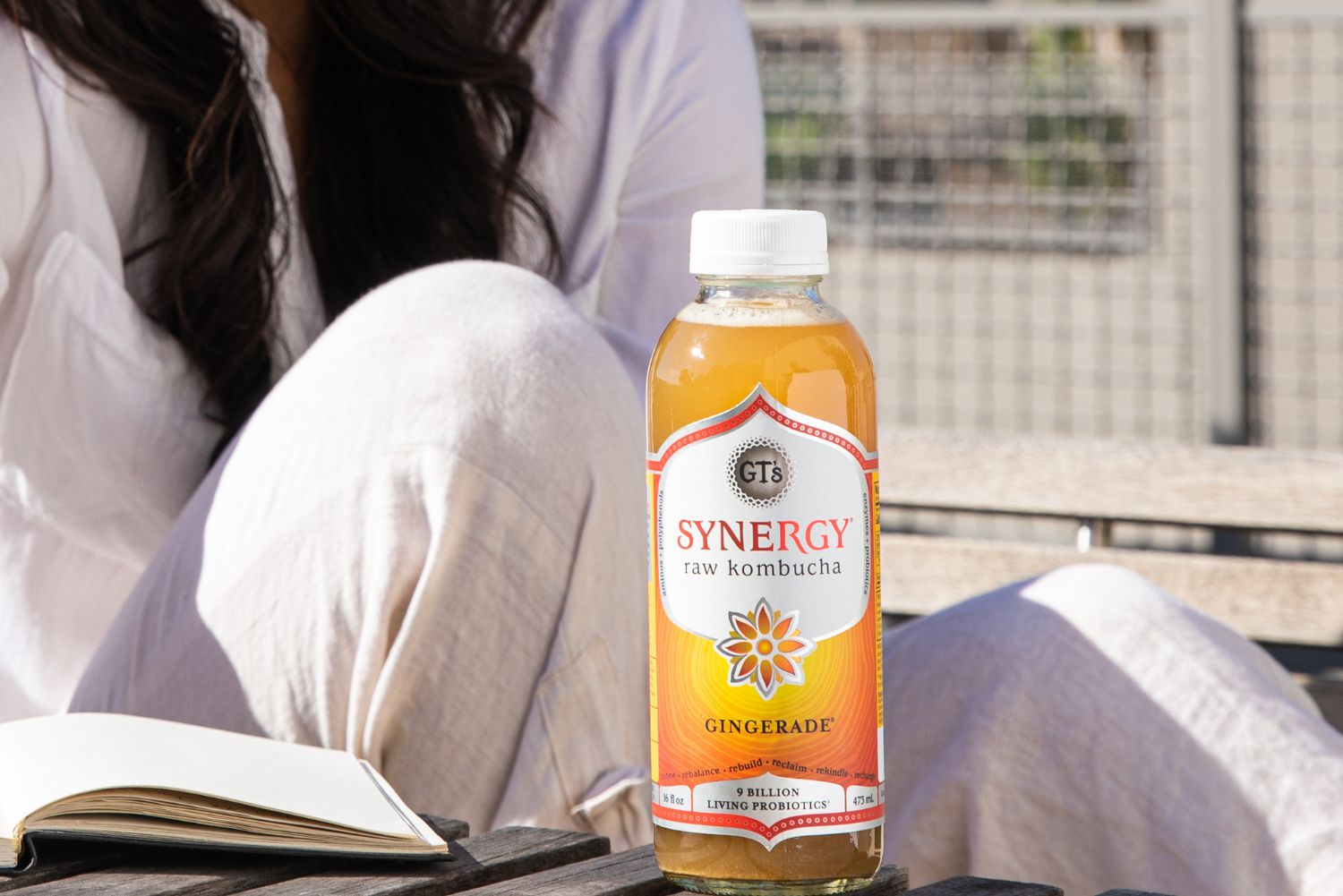 Woman reading book with Gingerade SYNERGY Raw Kombucha